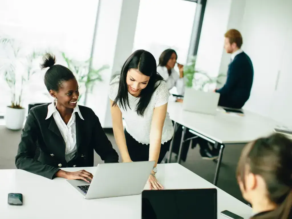 Equipe diversa trabalha reunida em torno de uma mesa com computadores.