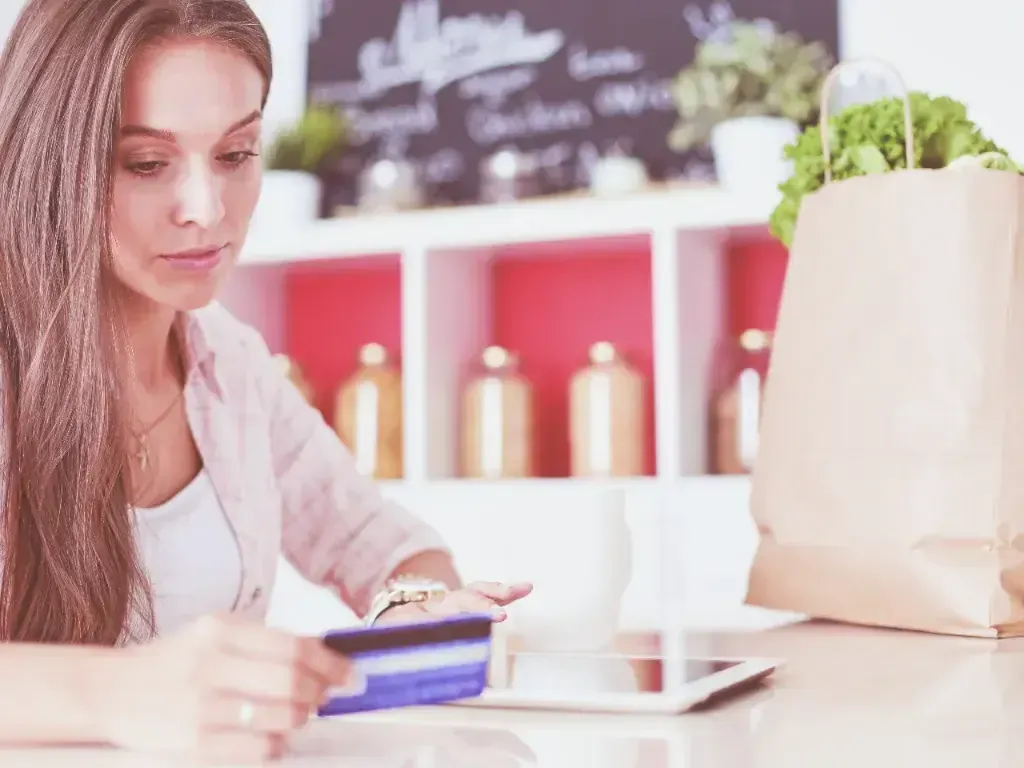 Mulher consulta um caderno ao lado de produtos expostos em prateleiras.